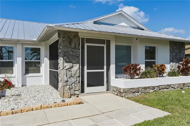 Property entrance featuring stone siding, stucco siding, and a standing seam roof