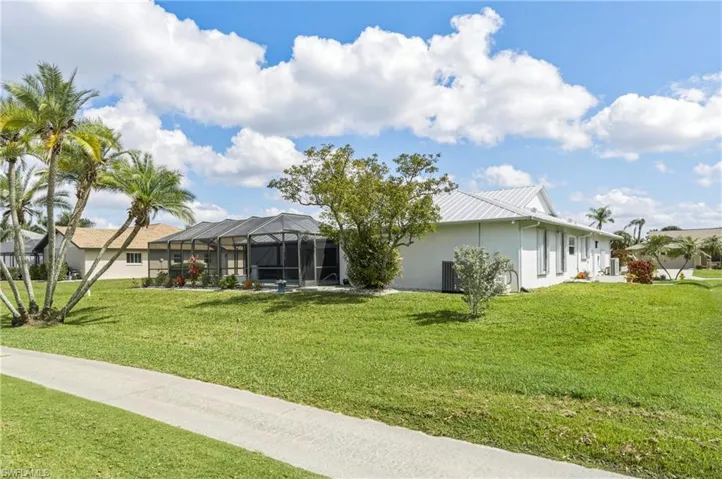 Back of property with a lawn, a lanai, a sunroom, and stucco siding