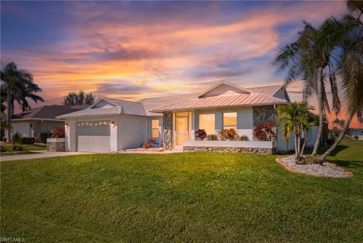 View of front of home featuring stone siding, a lawn, concrete driveway, an attached garage, and stucco siding