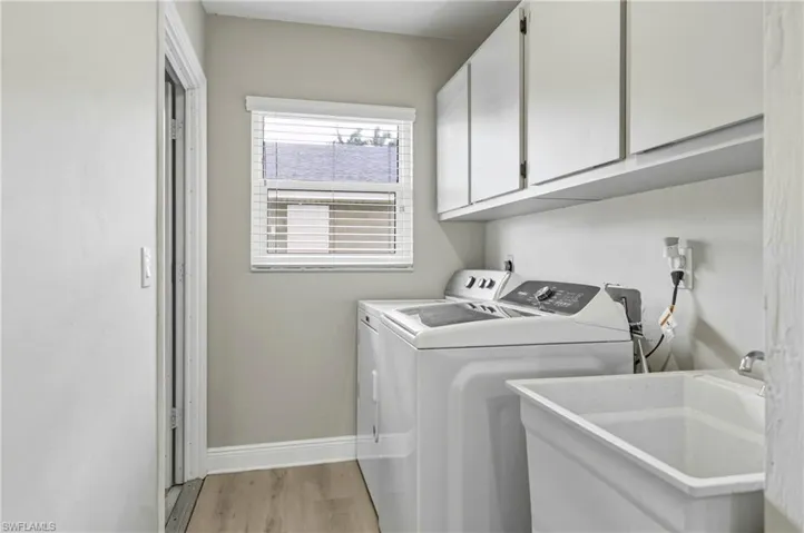 Laundry room with light wood finished floors, cabinet space, and washer and dryer