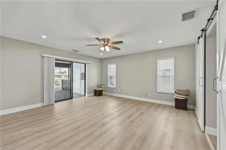 Unfurnished bedroom featuring a barn door, recessed lighting, access to exterior, light wood finished floors, and ceiling fan