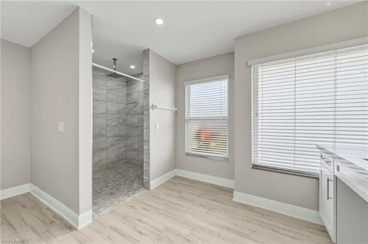 Full bath with light wood-style flooring, walk in shower, vanity, and recessed lighting