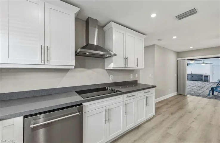 Kitchen featuring dishwasher, recessed lighting, white cabinets, light wood finished floors, and black electric stovetop