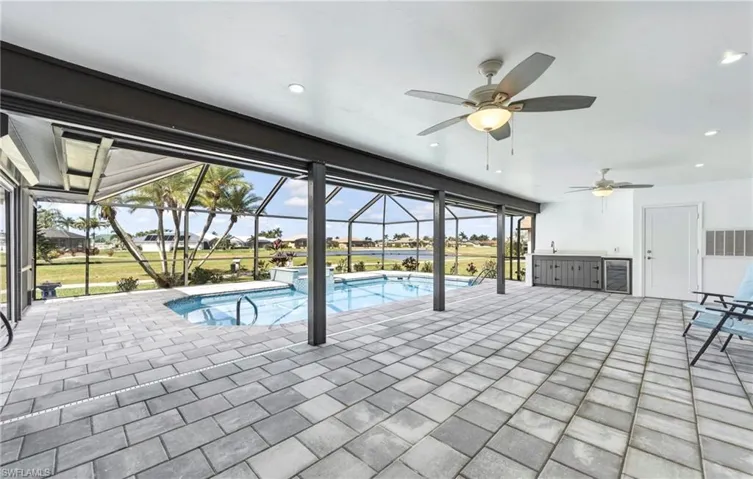 Integrated pool / hot tub featuring a sunroom, a patio, glass enclosure, and a residential view