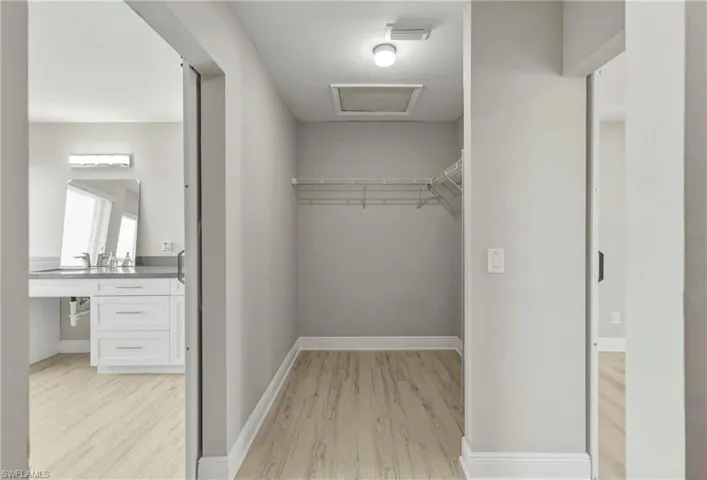 Walk in closet with attic access and light wood finished floors