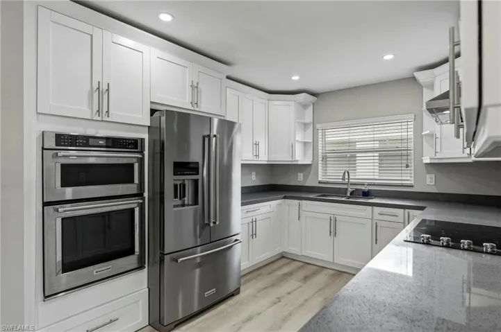 Kitchen featuring open shelves, stainless steel appliances, light wood-type flooring, white cabinets, and dark stone countertops