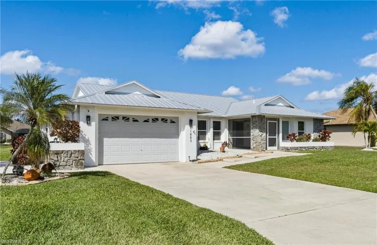 Single story home featuring a front lawn, a garage, concrete driveway, stucco siding, and a metal roof