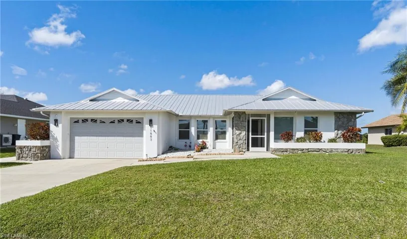 Single story home with stone siding, an attached garage, concrete driveway, and a front yard
