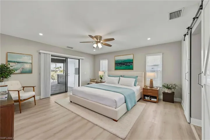 Bedroom featuring light wood-style floors, a barn door, access to exterior, recessed lighting, and ceiling fan