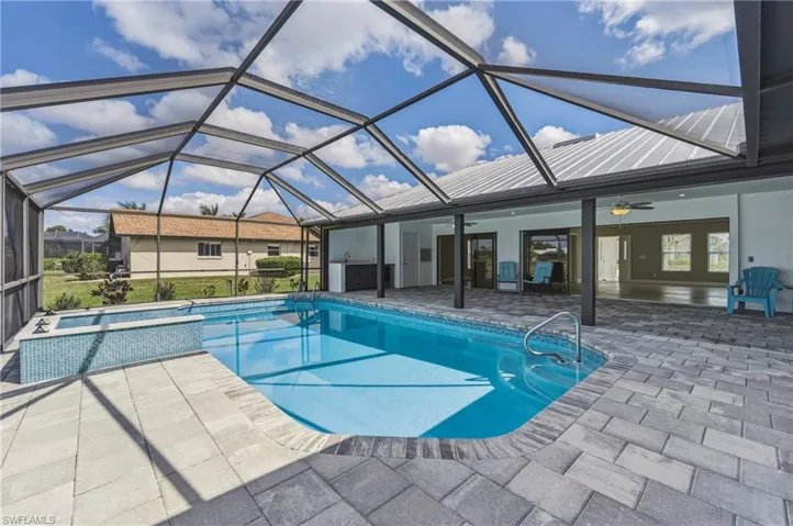 Outdoor pool featuring a sunroom, a lanai, a patio area, and a hot tub