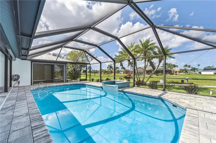 Combined pool / hot tub featuring a sunroom, a patio area, a lanai, and a yard