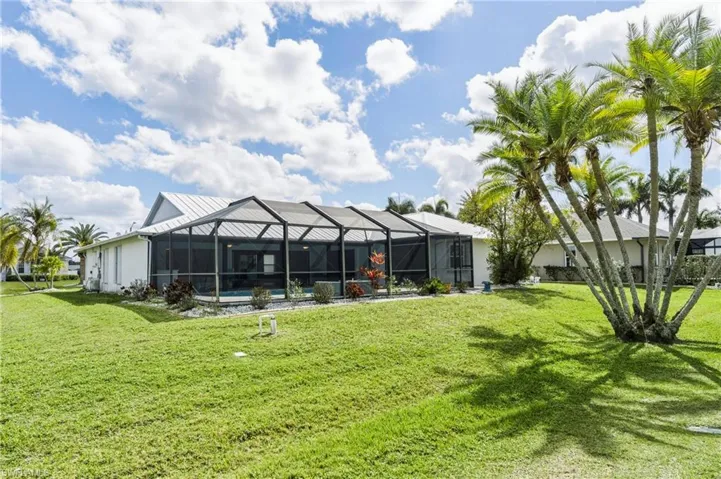 Back of property with a lanai, a yard, a sunroom, stucco siding, and a swimming pool