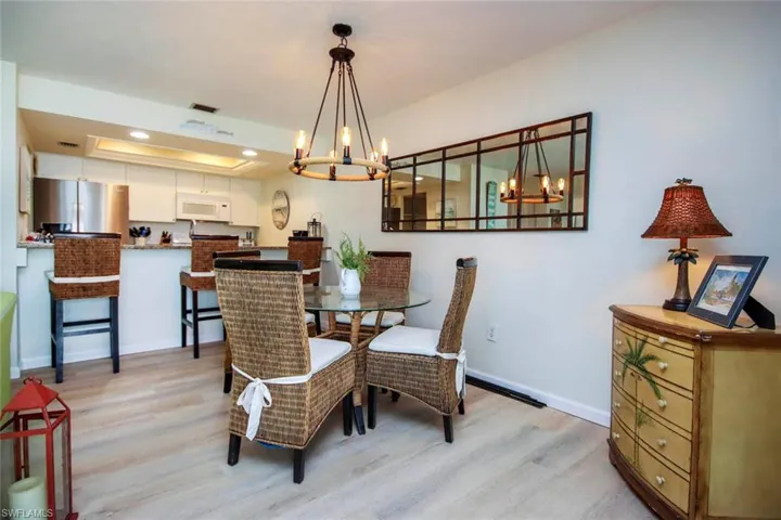 Dining space with a tray ceiling, light wood-type flooring, recessed lighting, and a chandelier