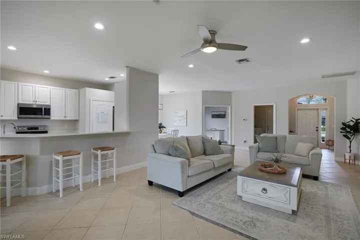 Open-concept living area featuring a kitchen pass-through with breakfast bar, recessed lighting, and tile flooring