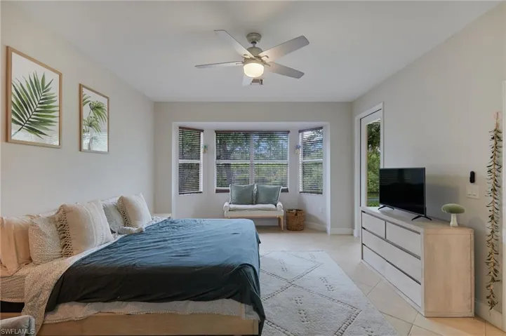 Spacious room featuring tile flooring, a bay window with blinds, and a contemporary ceiling fan with lighting