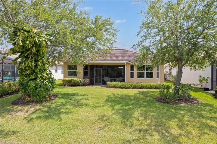 Expansive green lawn with mature trees framing the rear exterior