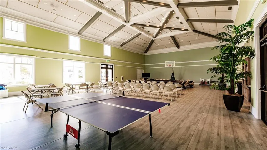 Recreation room featuring a towering ceiling and wood finished floors