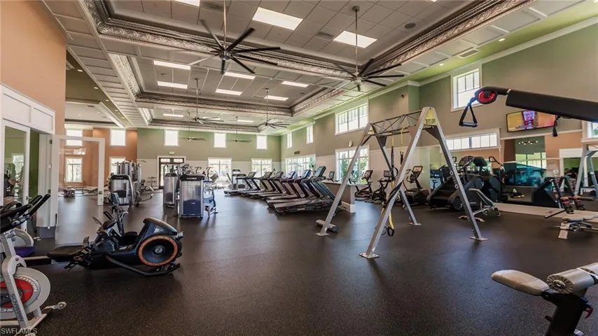 Gym with a ceiling fan, a high ceiling, crown molding, and a drop ceiling