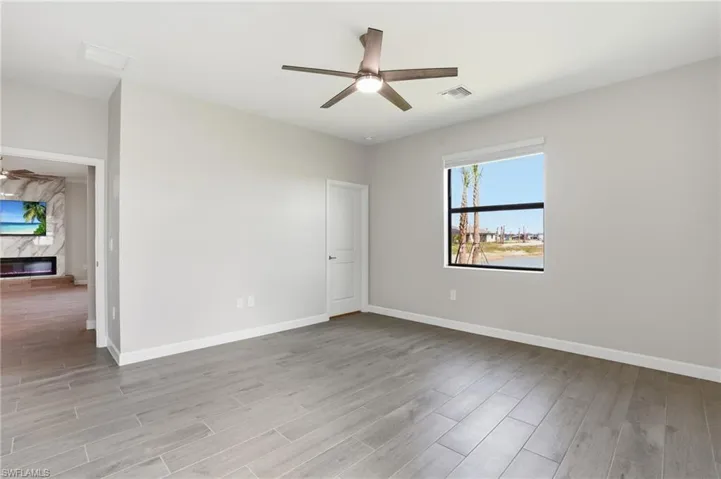 Spare room featuring ceiling fan, a premium fireplace, and light wood-type flooring