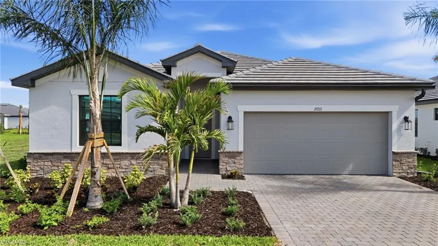 View of front facade featuring stone siding, decorative driveway, and an attached garage