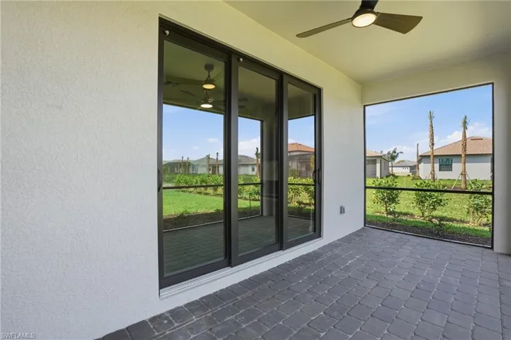 Unfurnished sunroom featuring a ceiling fan, a patio, and a residential view