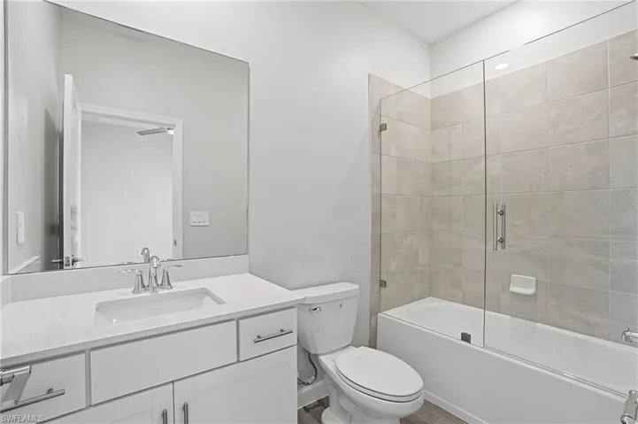 Bathroom with vanity and bath / shower combo with glass door