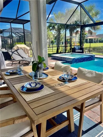 View of pool featuring a sunroom, a lanai, a pool with connected hot tub, and outdoor dining area
