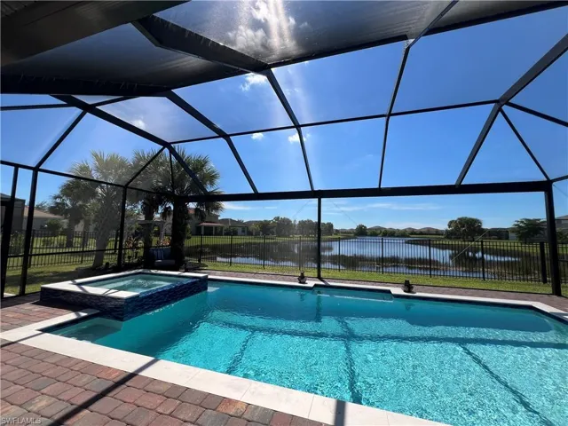 View of swimming pool featuring a water view, a sunroom, a pool with connected hot tub, and a lanai