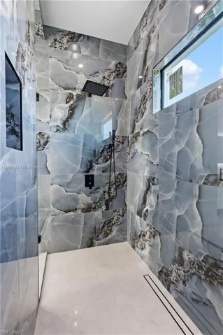Walk-in shower featuring full-height porcelain tile walls with a blue and grey veining pattern