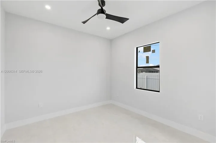 Room featuring light-toned flooring, crisp white walls, and a contemporary black ceiling fan with integrated lighting