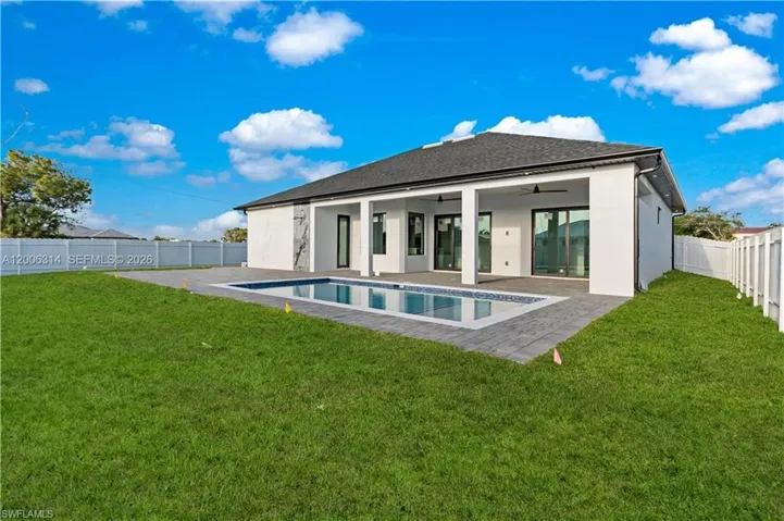 Contemporary white stucco exterior with a dark shingle roof and a private swimming pool