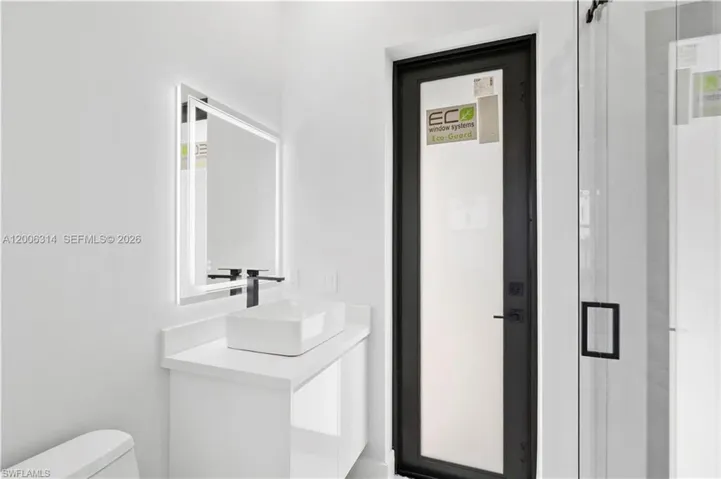 Modern vanity featuring a rectangular vessel sink, wall-mounted matte black faucet, and an illuminated mirror
