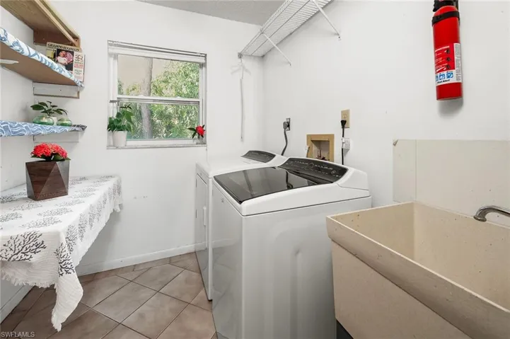 Laundry room featuring sink, washer, dryer and storage space.