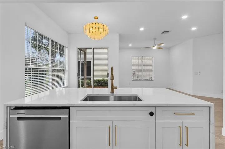 Kitchen featuring white cabinetry, sink, stainless steel dishwasher, and decorative light fixtures
