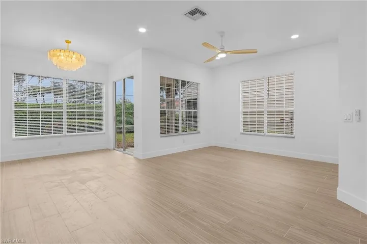 Spare room with ceiling fan with notable chandelier and light hardwood / wood-style flooring