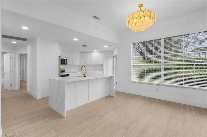 Kitchen featuring decorative light fixtures, tasteful backsplash, white cabinetry, sink, and stainless steel appliances