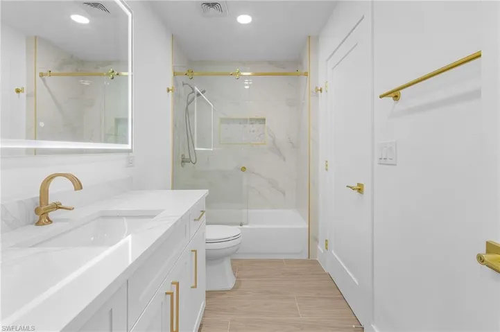 Full bathroom featuring shower / bath combination with glass door, vanity, and toilet
