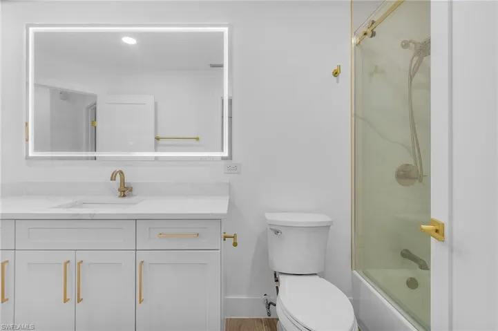 Full bathroom with vanity, combined bath / shower with glass door, and toilet