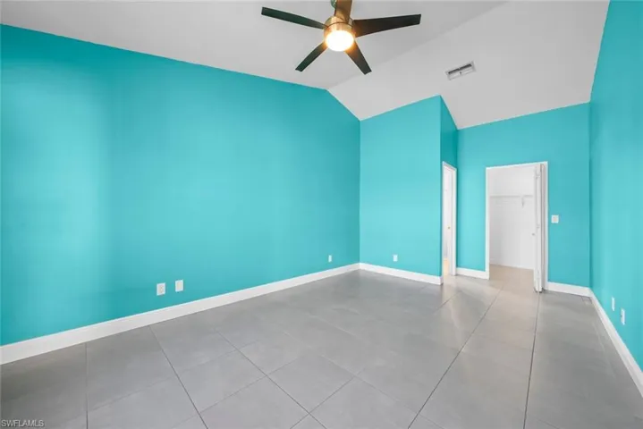Spare room featuring vaulted ceiling, ceiling fan, visible vents, and baseboards