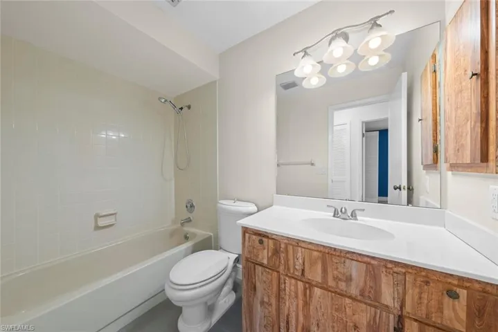 Full bathroom featuring tiled shower / bath combo, vanity, and toilet