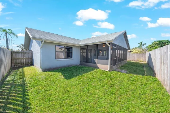 Rear view of property featuring a lawn and a sunroom