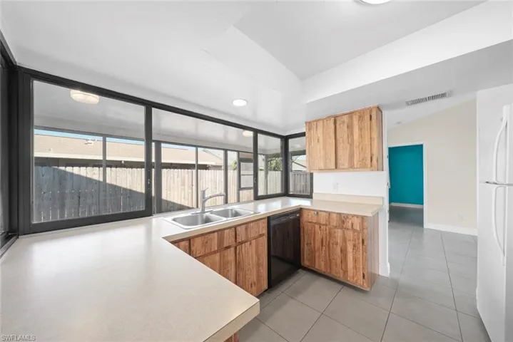 Kitchen featuring white refrigerator, sink, dishwasher, and light tile patterned floors