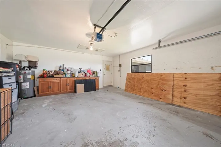 Garage featuring a garage door opener and electric water heater
