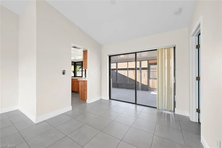 Tiled empty room with lofted ceiling