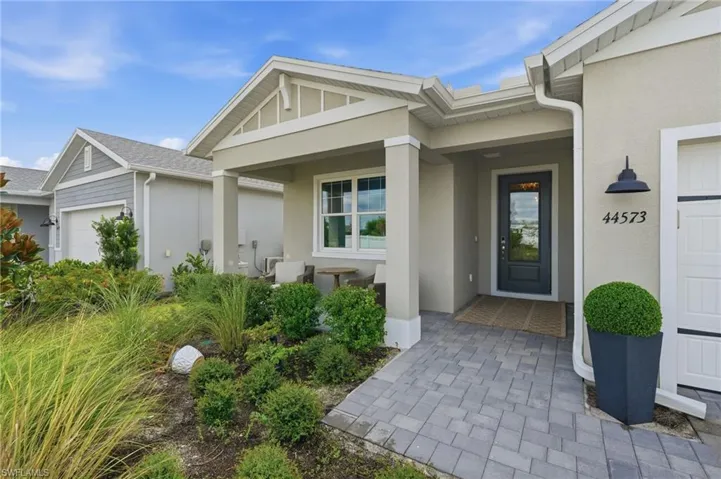Covered entry with columns, paver walkway, and a dark-paneled door with clear glass