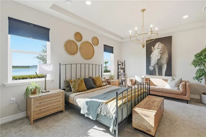 Recessed lighting, large windows with water scenery, tray ceiling, and a gold-tone chandelier