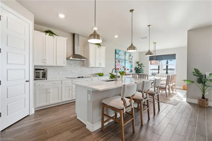 Open concept kitchen with wood-finish flooring, white cabinetry, a large kitchen island, and stainless steel appliances
