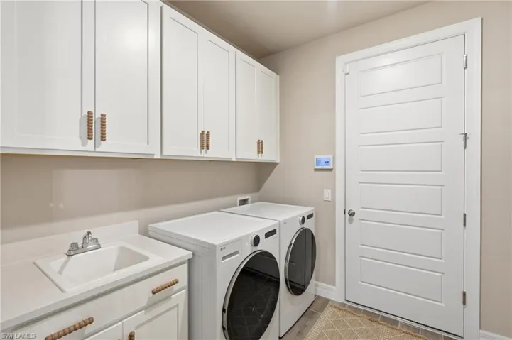 White shaker cabinetry, integrated utility sink, white paneled door, and durable flooring