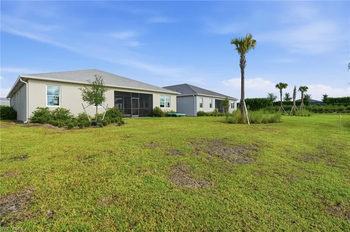Expansive yard featuring a screened patio, stucco exterior, and surrounding shrubbery