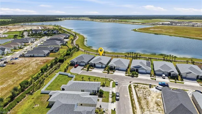 Lakeside community featuring single-story homes with attached garages, paved driveways, and manicured landscaping